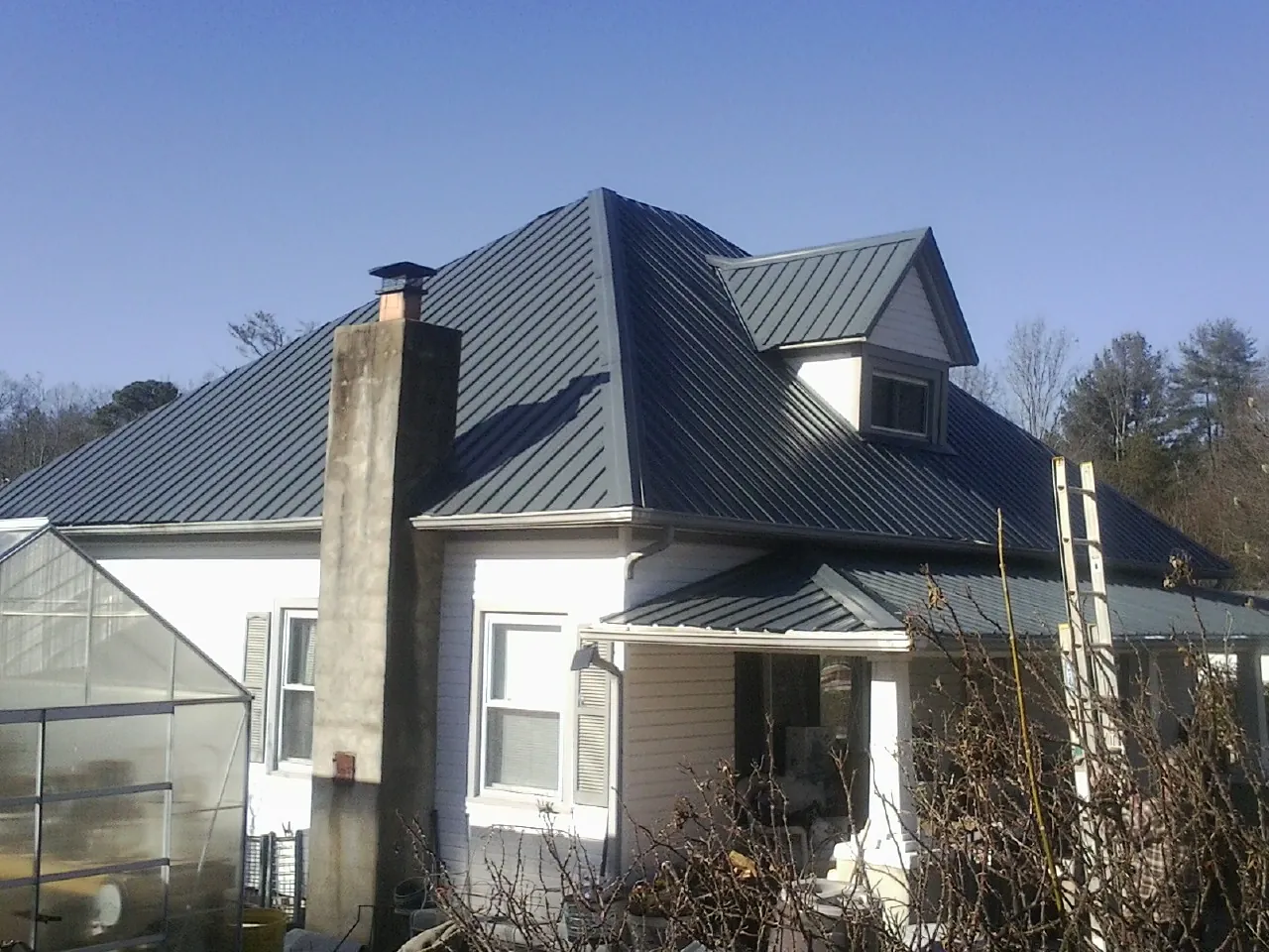 Dark blue standing seam metal roof on a white farmhouse with dormer — Slate & Tile Roof Repair by Roofing Brothers in Harrison Township