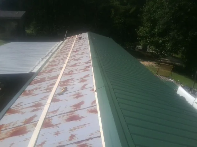 Old rusted panels beside newly installed green metal roofing — Wind Damage Roof Repair by Roofing Brothers in Harrison Township