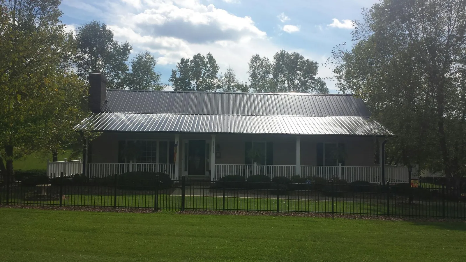 Gray metal roof on a brick ranch with a full width front porch — Gutter Guard Installation work by our crew in Harrison Township