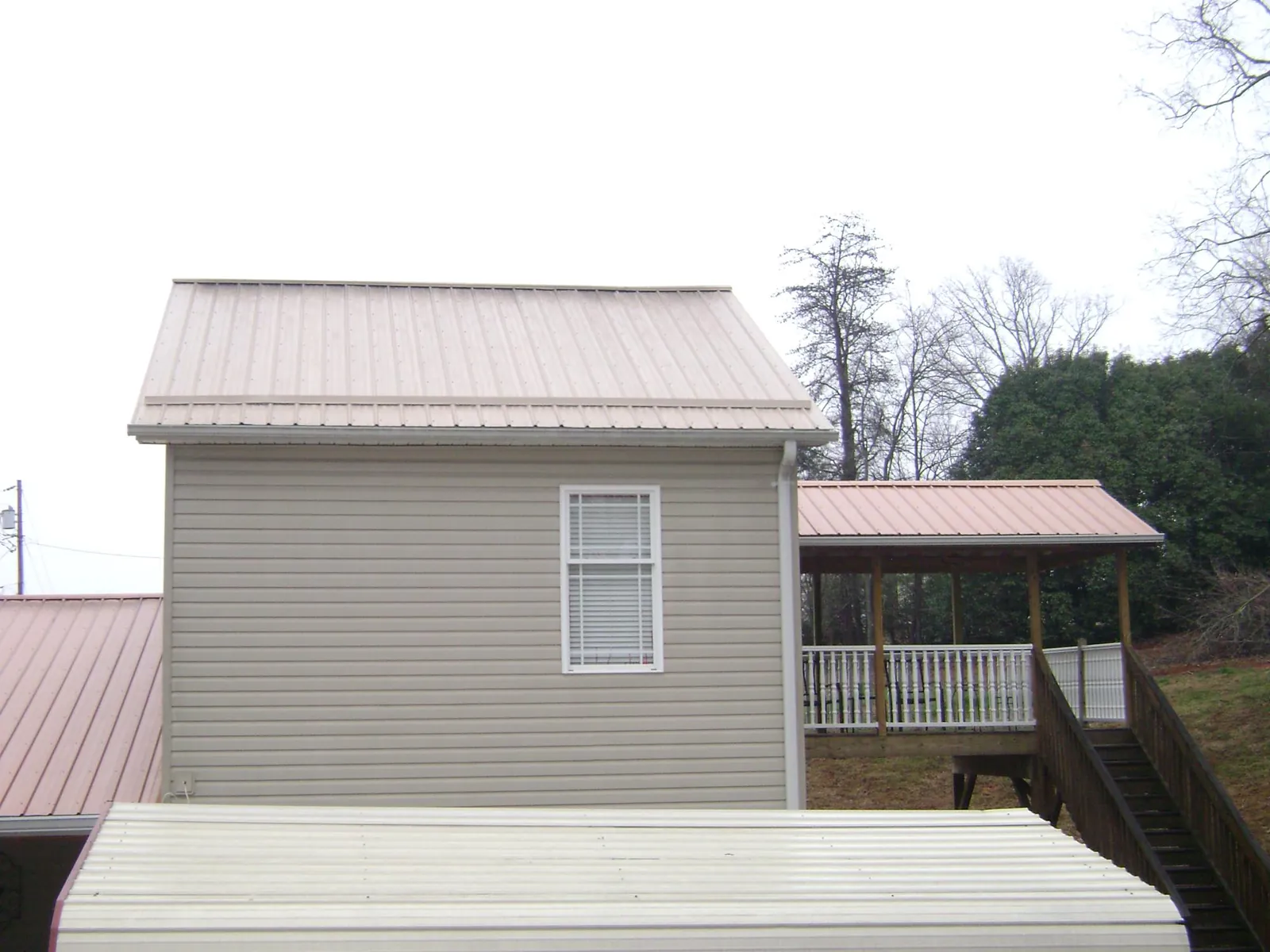 Tan metal roofs on a two story addition and attached porch, from a Roof Replacement job in Harrison Township