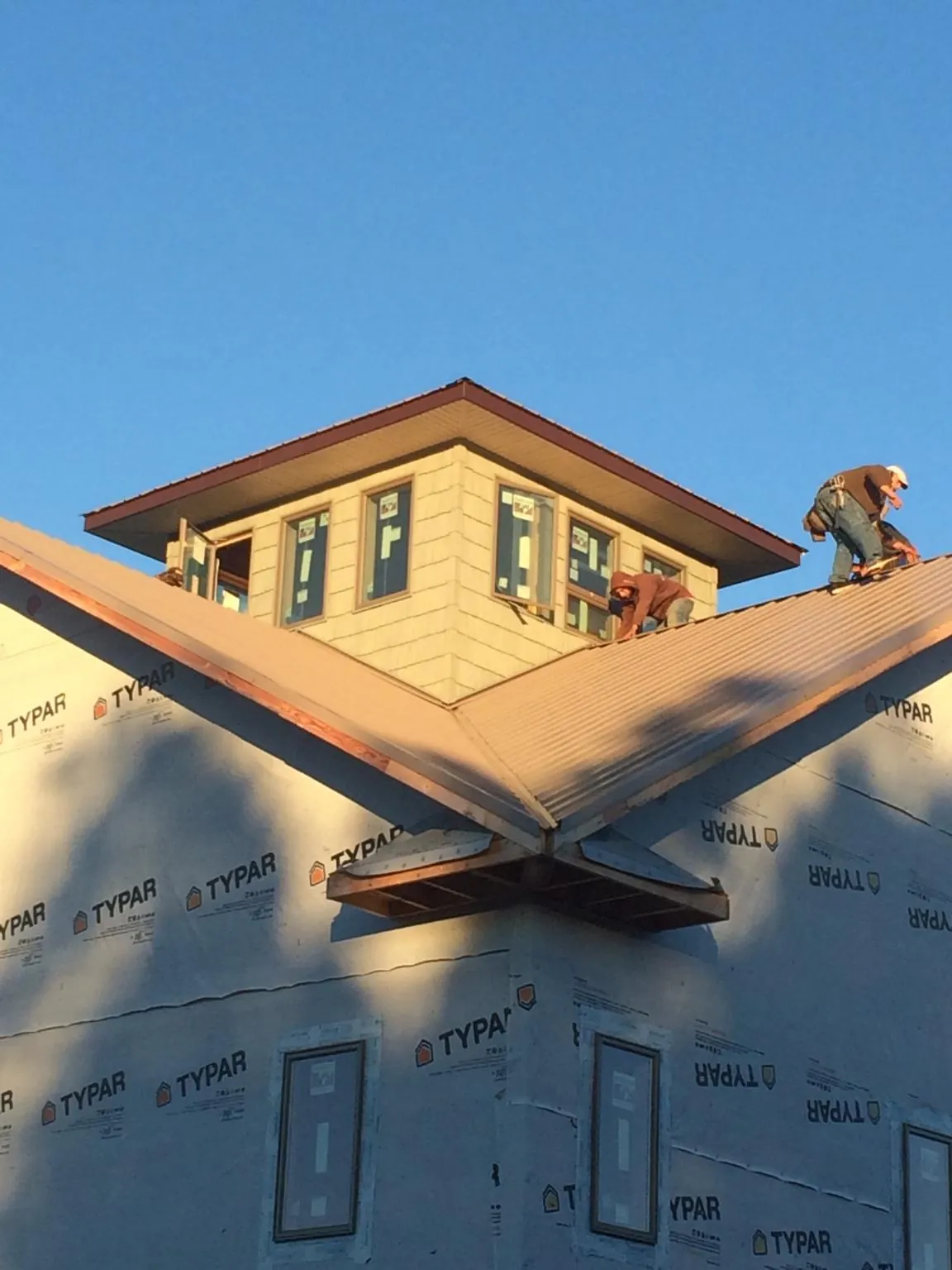 Roofers working around a rooftop cupola on a new metal roof at sunset — Roof Waterproofing in Harrison Township by Roofing Brothers